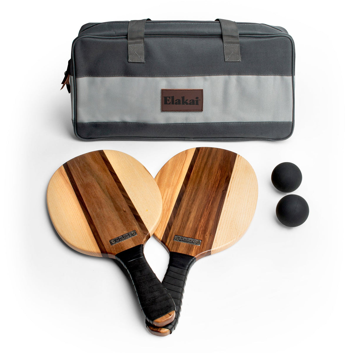 The Paddle Ball Set includes two wooden paddles with black handles, two black balls, and a gray Elakai-branded carrying bag—all showcased on a white background. Combining timeless design and premium materials, this set provides everything you need for hours of outdoor fun.