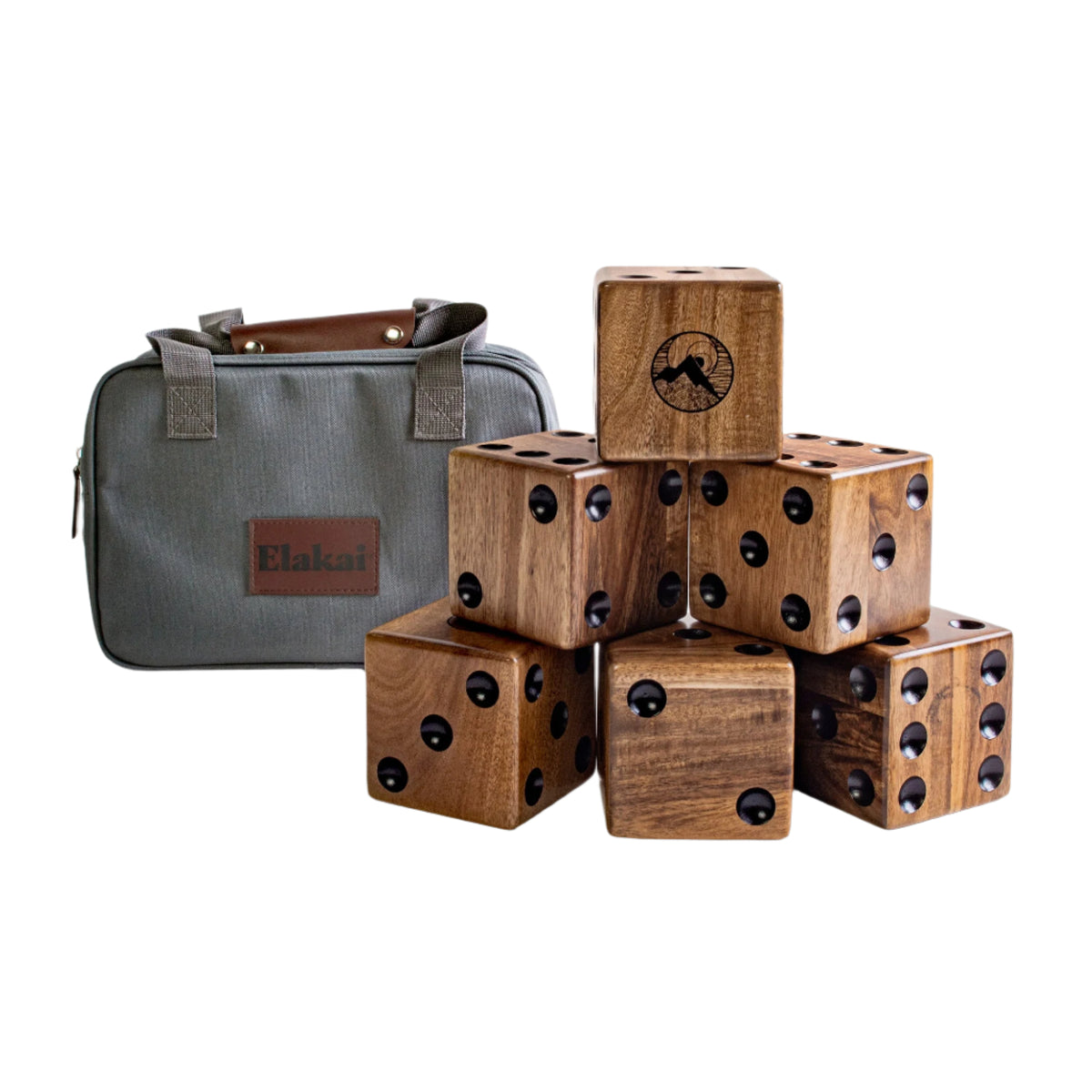 Six large Giant Wood Dice by Elakai are stacked in a pyramid next to a green carrying case with brown handles and a leather patch labeled Elakai. Perfect for outdoor game nights, these dice feature bold black dots, with one die displaying an eye-catching mountain design.