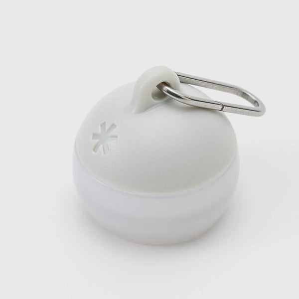 A small round white plastic container with a metal carabiner attached at the top, photographed on a clean white background.