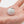 Small white device with a keychain attachment held in a hand against a neutral background