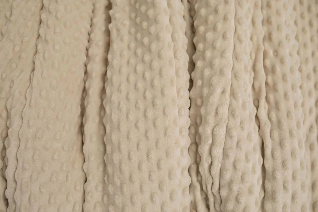 Close-up of the Erin Luxe Blanket by Beddy’s, featuring a soft, beige minky fabric with raised, evenly spaced dots and vertical ridges that add cozy texture to its surface.