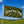 Green flag with 'Airstream' text waving in the wind against a blue sky and green landscape.