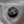 Close-up of a black plastic cap or valve fitting attached to a circular opening on a light gray fabric surface.