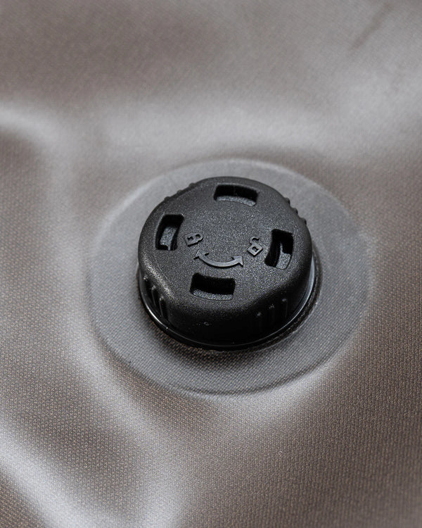 Close-up of a black plastic cap or valve fitting attached to a circular opening on a light gray fabric surface.
