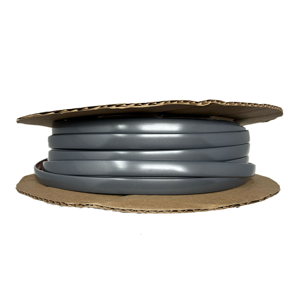 A coil of Airstream Premium Replacement Belt Trim for Travel Trailers, made from gray plastic, is wrapped around flat, circular cardboard pieces and viewed from the side against a white background.