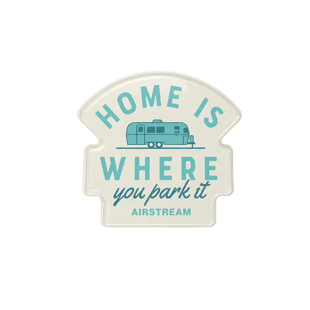 A die-cut vinyl sign with a vintage-style cream background and turquoise lettering that reads 'HOME IS WHERE you park it' with 'AIRSTREAM' at the bottom, featuring a small turquoise retro camper illustration. The sign is photographed against a neutral light gray background.