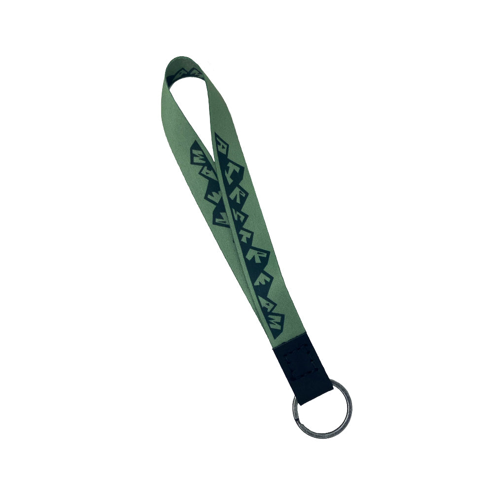 Introducing the Airstream Horizons Wristband Keychains: a green fabric keychain loop featuring a black geometric pattern, complemented by a sturdy metal keyring attached to a black leather end—making it the perfect stylish accessory for your everyday carry.