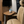 Beige leather recreational vehicle cab seat with a fold-out wooden side table, wall-mounted TV, and a blue and white mug on a phone inside the cab.
