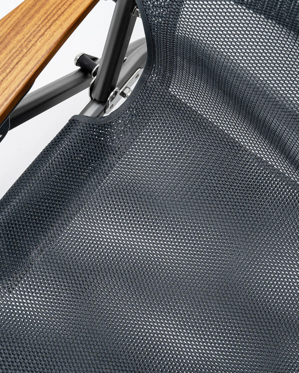 Close-up of a textured chair seat with a wooden armrest.