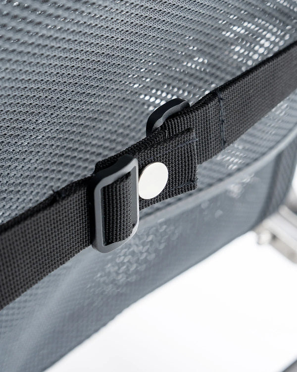 Close-up of a black strap with a buckle on a textured gray surface