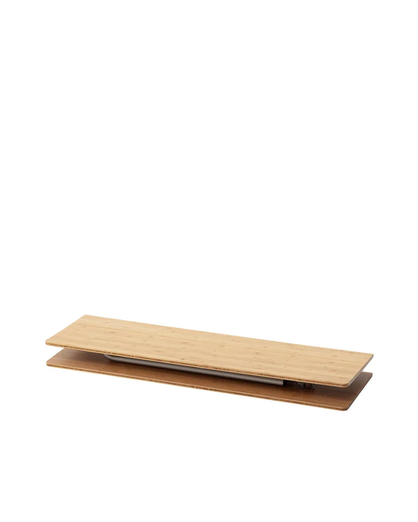 A rectangular, light wood-colored Snow Peak Large Renewed Single Action Table with a minimal, flat design is shown folded and closed against a plain white background. Featuring a laminated bamboo worktop and sturdy aluminum legs, this table offers both durability and modern style for your workspace.