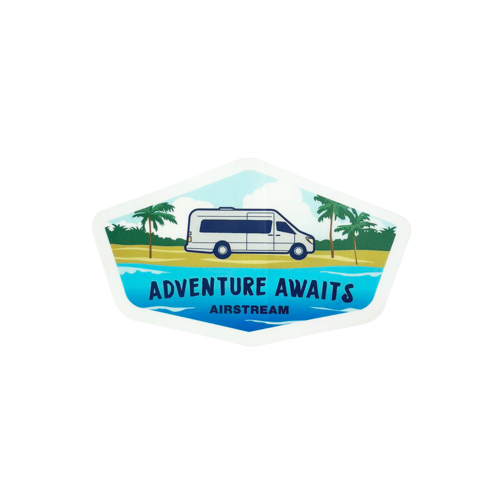 A vibrant sticker titled “Airstream Touring Coach Beach Sticker” features a motorized Airstream camper van parked by palm trees and water, with the phrase “ADVENTURE AWAITS AIRSTREAM” set against a bright, tropical backdrop.