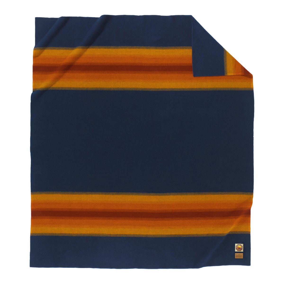 The National Park Blanket by Pendleton is an American-made navy blue wool blanket designed with bold horizontal orange and gold stripes near the edges. A small label is sewn on the bottom left corner, and the folded top right corner reveals the reverse side, echoing Pendleton’s classic National Park Blanket style.
