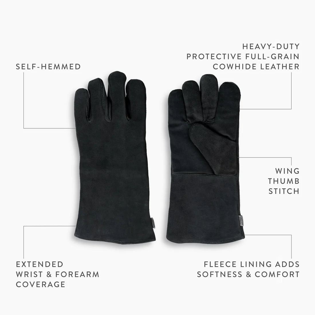 Two Open Fire Gloves by Barebones made of heavy-duty black cowhide leather are shown, one palm up and one palm down. Labels highlight features such as a self-hemmed edge, extended wrist coverage for heat protection, wing thumb stitch, soft fleece lining for comfort, and durable cowhide leather construction.