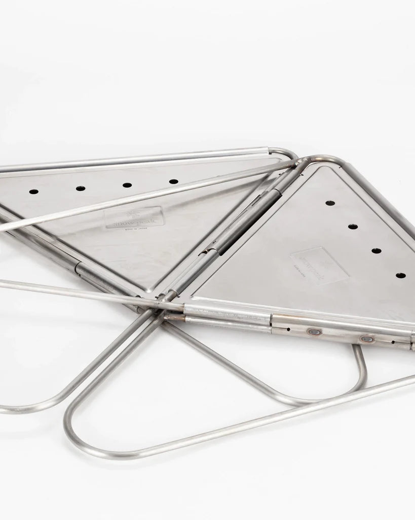 Two folded, triangular stainless steel Snow Peak Pack & Carry Large Fireplace grills with perforated surfaces and tubular frames, positioned overlapping each other on a white background—perfect companions for your Pack & Carry Large Fireplace or any portable fireplace setup.