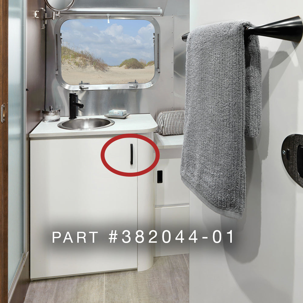 A modern RV bathroom showcases a sink, gray towel, and window overlooking sand dunes. A red circle marks a cabinet spot ideal for installing the Airstream Interior Pull Handle | Part # 382044 Series—an essential replacement handle for your Airstream.