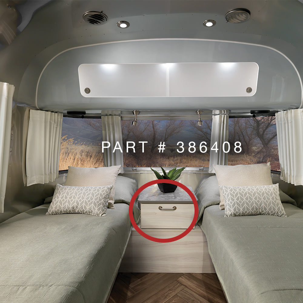 Interior of a modern RV featuring two twin beds with patterned pillows, a central nightstand adorned with a plant, and the Airstream Interior Pull Dot Handle in brushed nickel and red. Text reads “Airstream Interior Pull Dot Handle | Part # 386408” over the image—ideal for those searching for genuine Airstream parts.