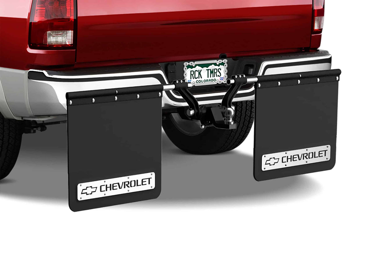 Rear view of a red pickup truck with a Colorado license plate, two large black Rock Tamer Truck Make Plates featuring Chevrolet logos for a custom look, and a towing hitch attached.