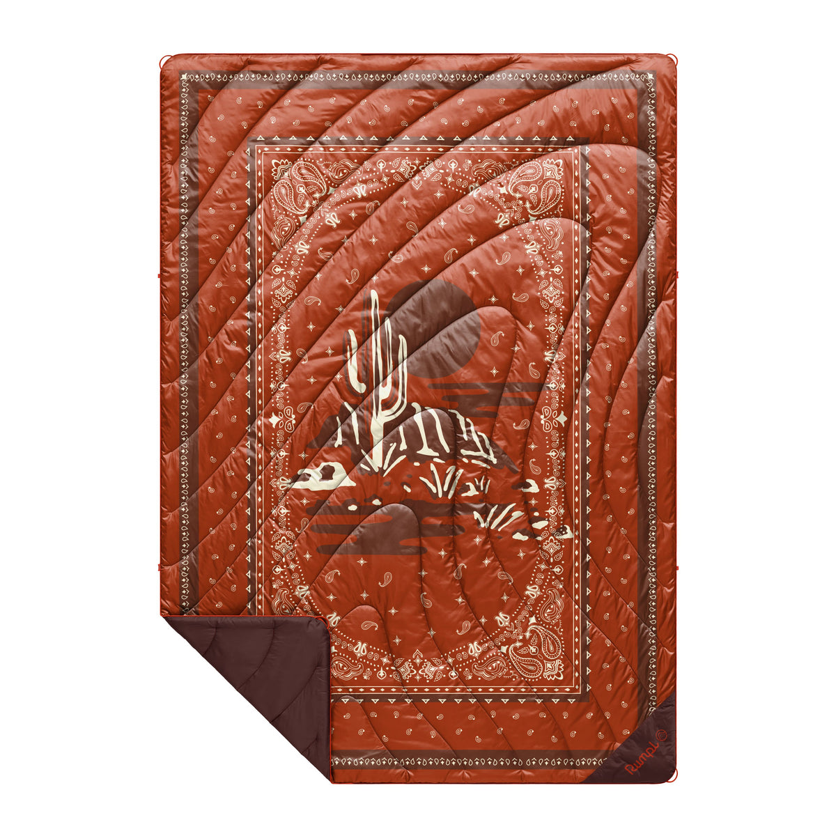 The Western Original Puffy Blanket by Rumpl features a rust-colored bandana pattern with a stylized white animal skeleton at the center. A folded corner reveals its solid brown underside and cozy synthetic insulation—making this outdoor blanket perfect for use as a sleeping bag blanket on cool nights.