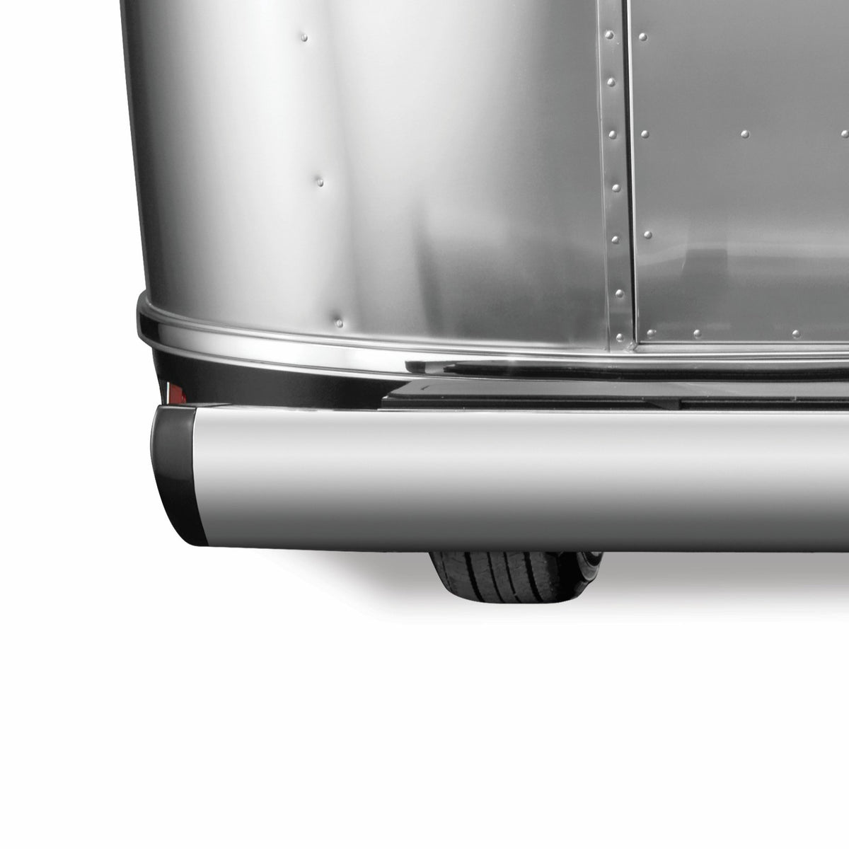 Close-up of the back corner of a shiny silver trailer, featuring part of a rounded bumper fitted with Airstream Black Bumper End Cap (Part # 382289-01, 382289-02) and one visible tire beneath the trailer.