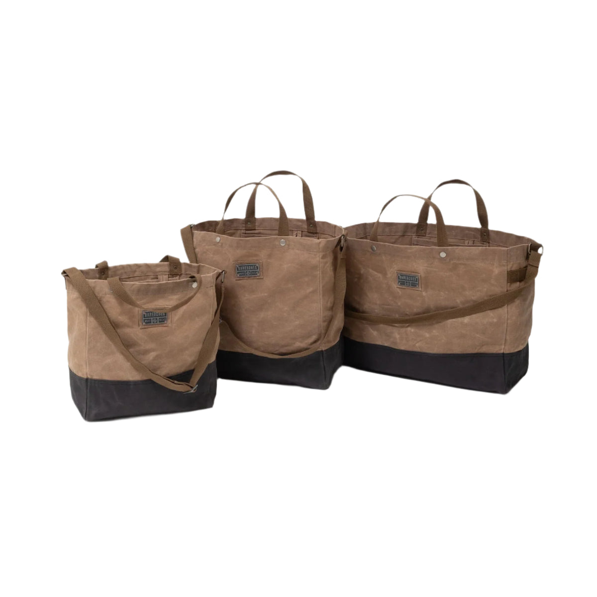 Three Neelum Tote Bags by Barebones in brown and black waxed canvas, each in a different size, are displayed against a white background. Featuring short handles and an adjustable shoulder strap, these reusable bags are crafted from heavy-duty canvas for lasting durability and versatile style.