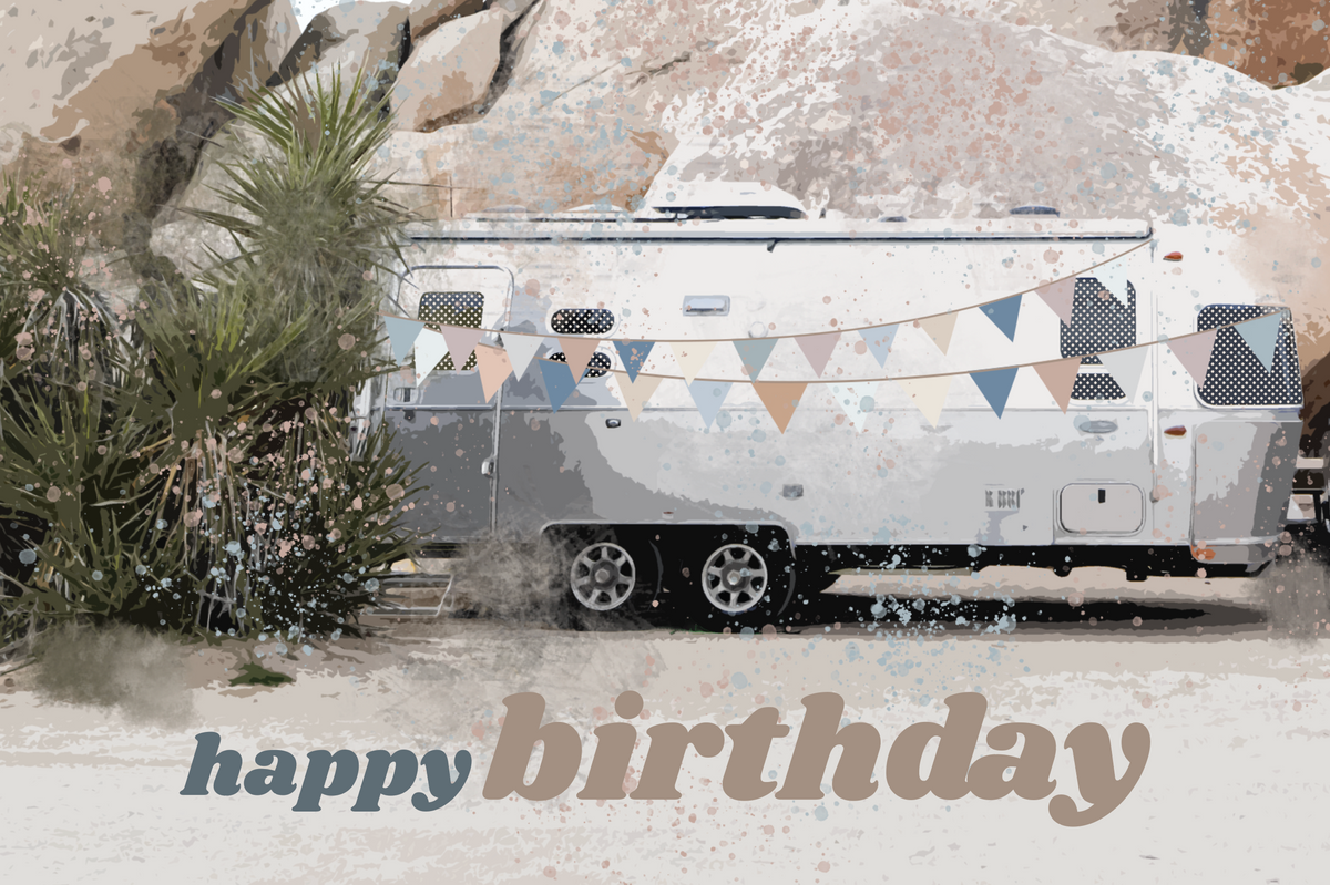 A gleaming white camper, inspired by classic Airstream trailers, is adorned with soft pastel pennant banners and rests beside sunlit desert rocks and shrubs. “Happy Birthday” appears in bold, artful lettering at the bottom, making this card from the Airstream Assorted Occasion Cards collection a charming choice for any greeting card set or unique occasion.