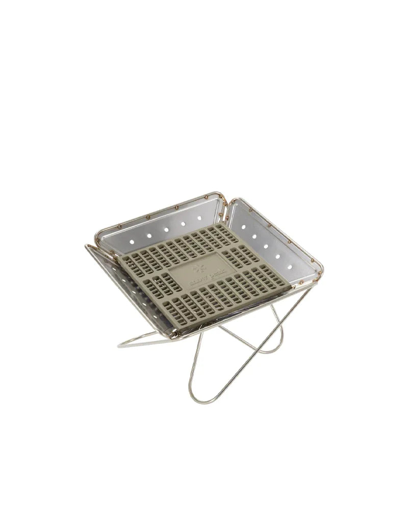 A compact, portable metal fire pit featuring a square design, perforated grate, and foldable legs—perfect for use as a charcoal grill or as the Snow Peak Fireplace Coal Bed. Shown against a plain white background, this versatile product draws inspiration from the renowned functionality of the Snow Peak Takibi and is ideal for outdoor gatherings.