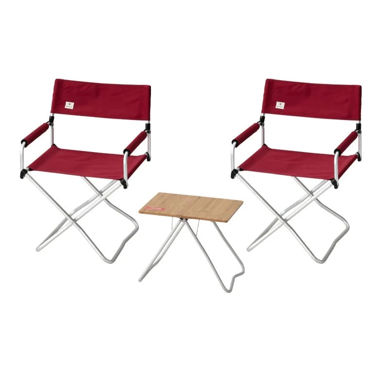 The Snow Peak Red Lounge Set features two red folding chairs with metal frames positioned on either side of a small rectangular wooden table with metal legs, all set against a white background for a stylish presentation.
