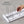 A hand adjusts steel dividers on a white base. Text reads: Adjustable. The Airstream StoreMore Roof Locker Dish Rack by YouCopia features 10 coated steel dividers that can be customized to fit your needs. Rearrange the slots easily to organize kitchen items—perfect for keeping your dishes secure in your Airstream or at home.