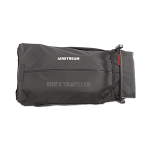 The Weber Traveler Cargo Protector is a black, folded carrying bag featuring AIRSTREAM and Weber Traveler labels, equipped with a zippered closure and handle for convenient transport or storage of grilling tools, displayed against a white background.