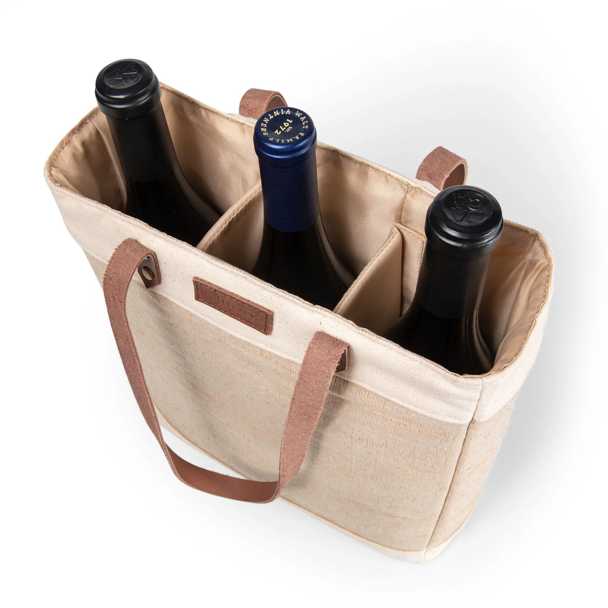 The Airstream Insulated 3 Bottle Wine Bag, shown from above in beige fabric with brown handles, is divided into three sections, each securely holding a dark glass wine bottle with caps in different colors.