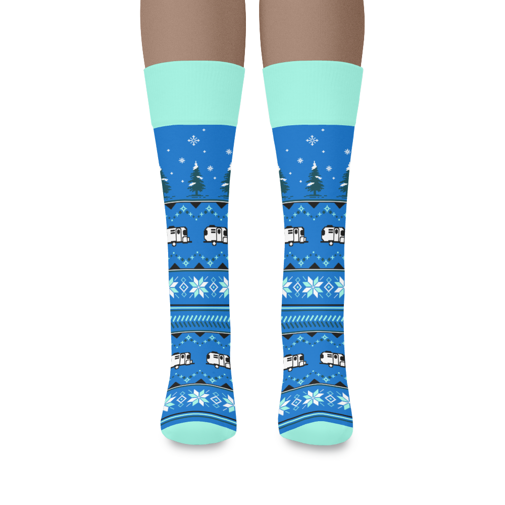 Airstream Winter Wonderland Socks: Blue knee-high winter socks with light blue cuffs, toes, and heels, adorned with a cozy pattern of snowflakes, pine trees, and white RVs for a festive winter-themed look.