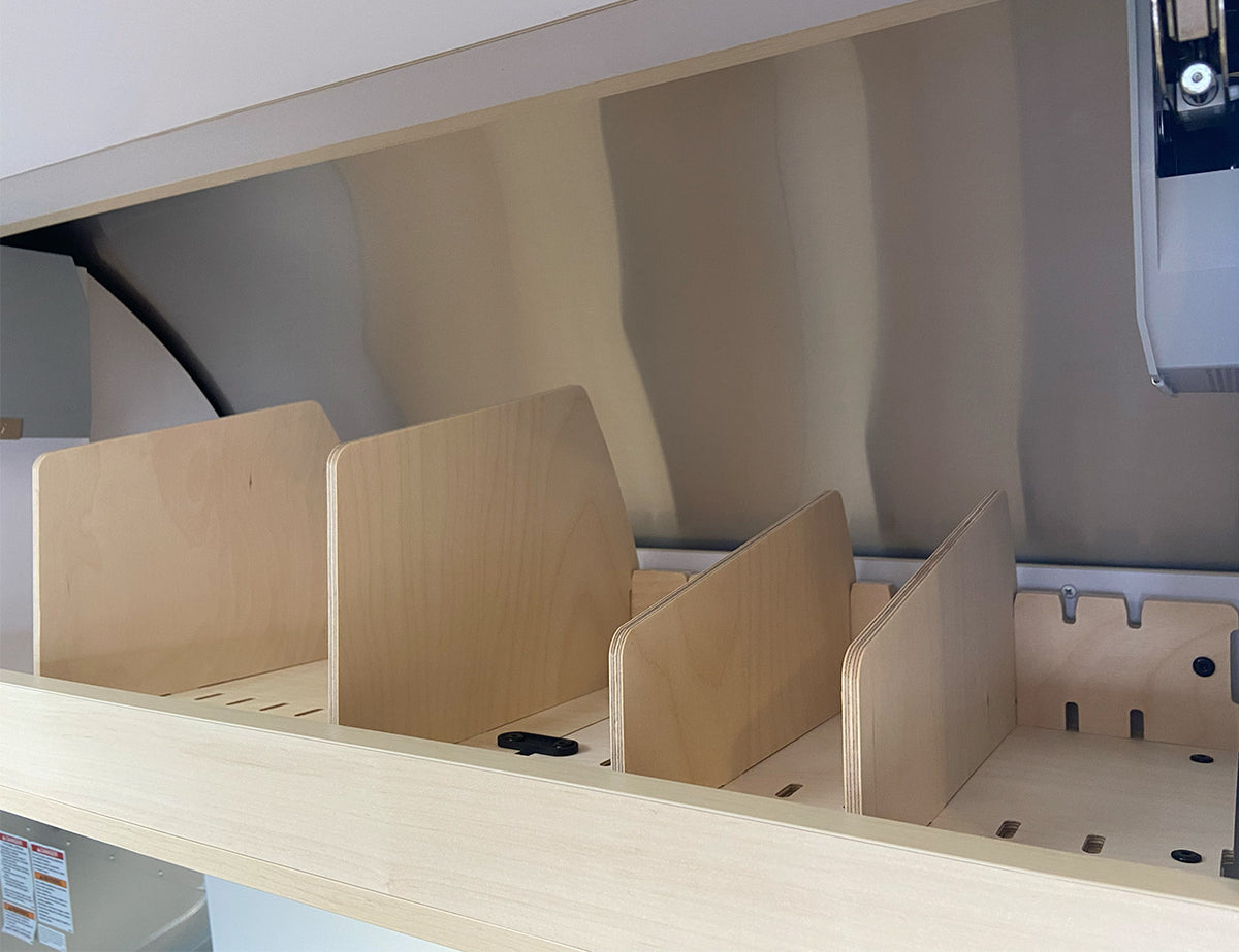 Four wooden vertical Dividers for Universal Roof Locker Organization by Airworthy Equipment Company are installed in a light-colored shelf, creating separate storage sections. These dividers provide a sleek solution to enhance the functionality of modern cabinets or storage units, making them ideal Airstream Travel Trailer accessories.
