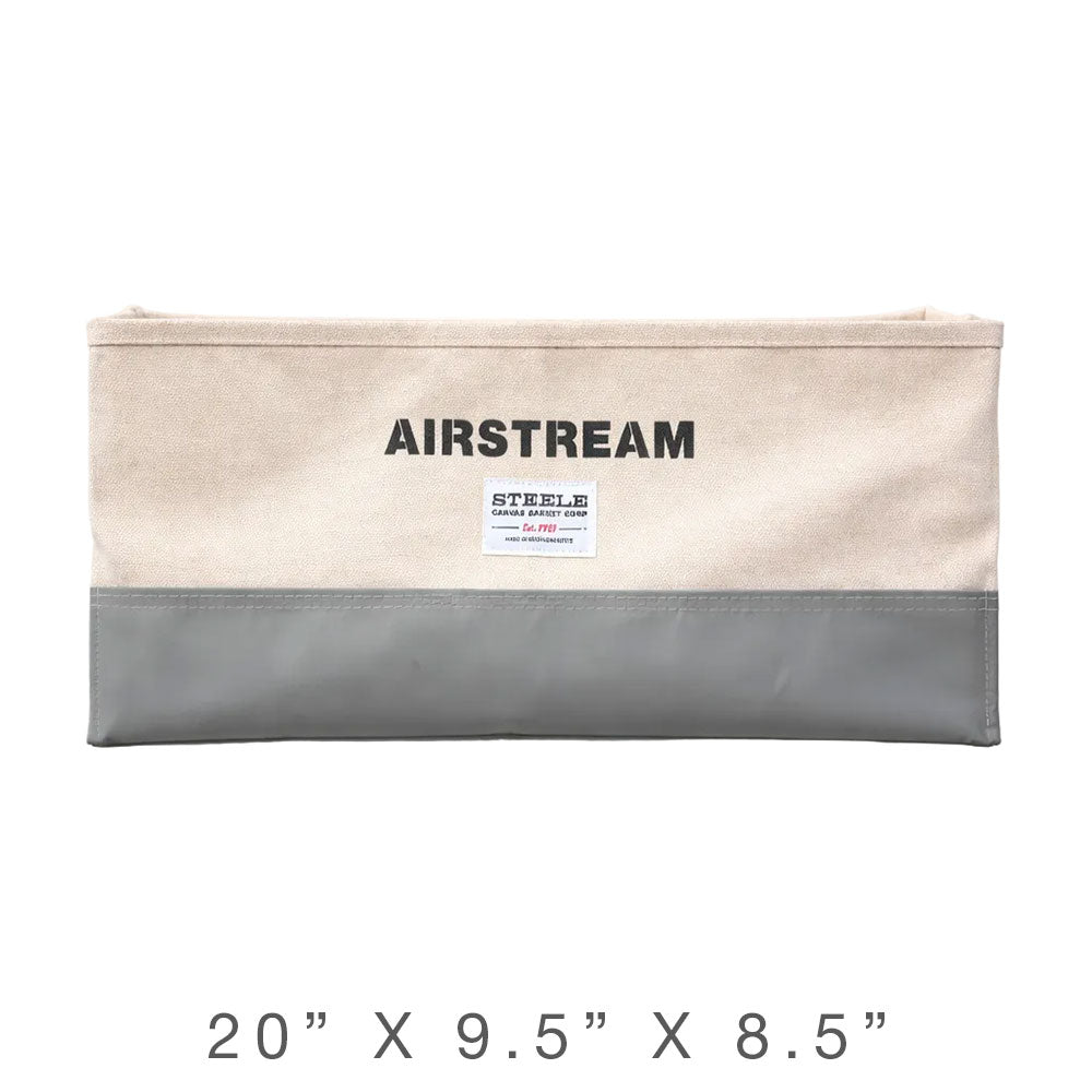 The Airstream x Steele Canvas Custom Storage Bins feature a rectangular design measuring 20 x 9.5 x 8.5 inches, with a beige fabric top and gray bottom, plus a central white label—ideal for keeping your travel trailer organized.