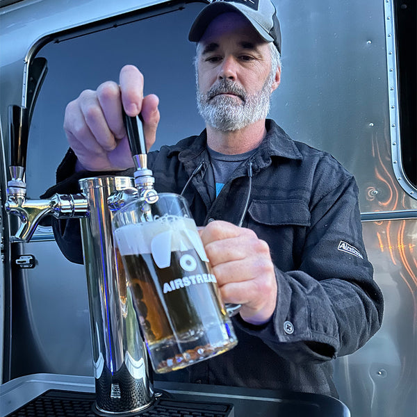 Man pouring beer from a tap into a glass with 'Airstream' branding.