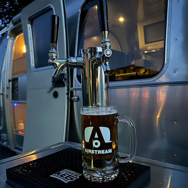 Glass of beer with a tap in front of an Airstream trailer