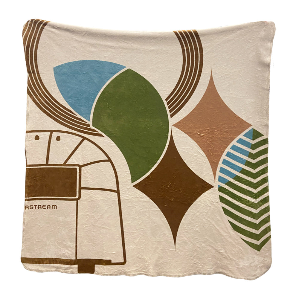 Introducing the Frank Lloyd Wright x Airstream Blanket, featuring a retro-inspired design with geometric leaf and diamond patterns in shades of green, brown, and blue. A subtle outline of an Airstream trailer appears on the left side, while the cream-colored background enhances the blanket’s luxurious feel and classic charm.