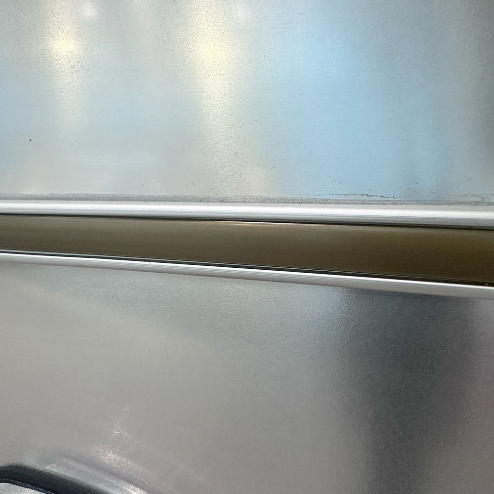 Close-up of a smooth metallic surface with a horizontal strip and soft reflections, featuring subtle gradients of silver with hints of blue and gold—perfectly capturing the refined look of the Airstream Premium Replacement Belt Trim for Travel Trailers.