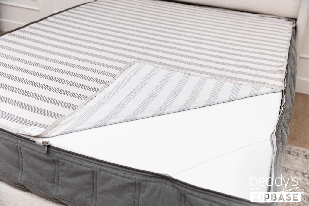 Airstream RV Fit Beddy’s for Flying Cloud Travel Trailers features a striped cover that’s partially unzipped to reveal a white interior layer—ideal for anyone looking for convenient, zippered bedding solutions. The words Beddy’s with ZIPBASE are shown in the lower right corner.