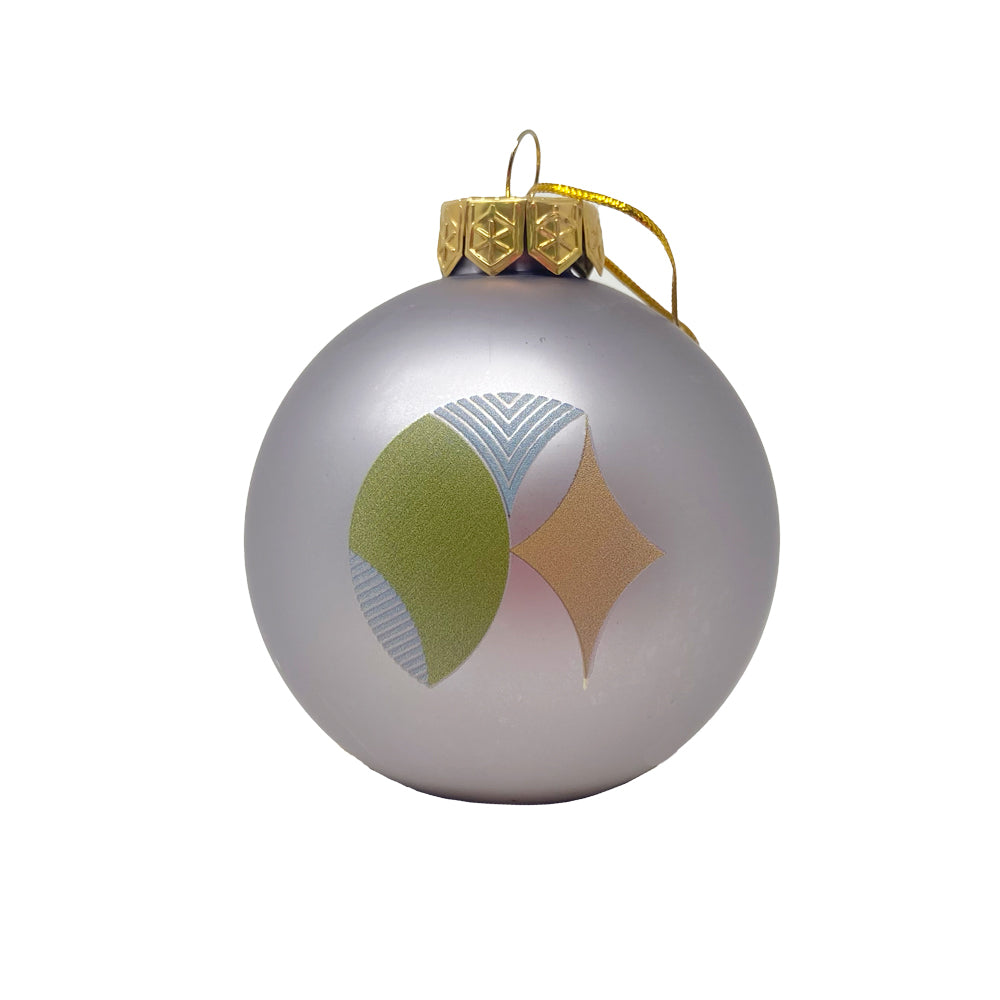 The Frank Lloyd Wright x Airstream Globe Ornament is a silver glass ornament with a gold cap and string, showcasing a modern geometric design in green, blue, and gold inspired by Frank Lloyd Wright.