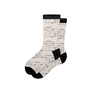 A pair of crew socks with a black and white retro trailer truck pattern, featuring solid black heels, toes, and cuffs, displayed on a clean white background.