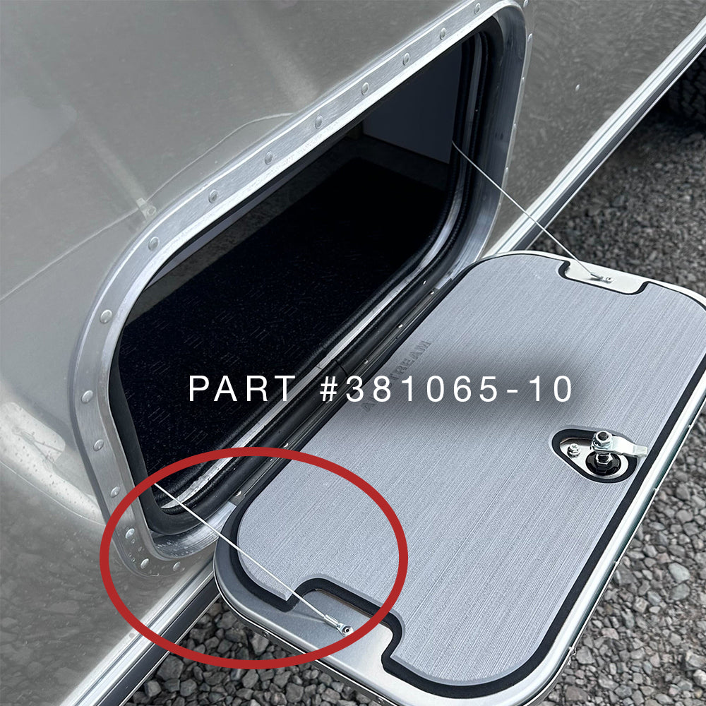 A close-up of an RV exterior compartment door, partially open, showcases the Airstream Cable Support for Exterior Compartment Doors | Part # 381065-10, with a red circle highlighting a key feature—perfect for those looking to replace or inspect Airstream cable support components.