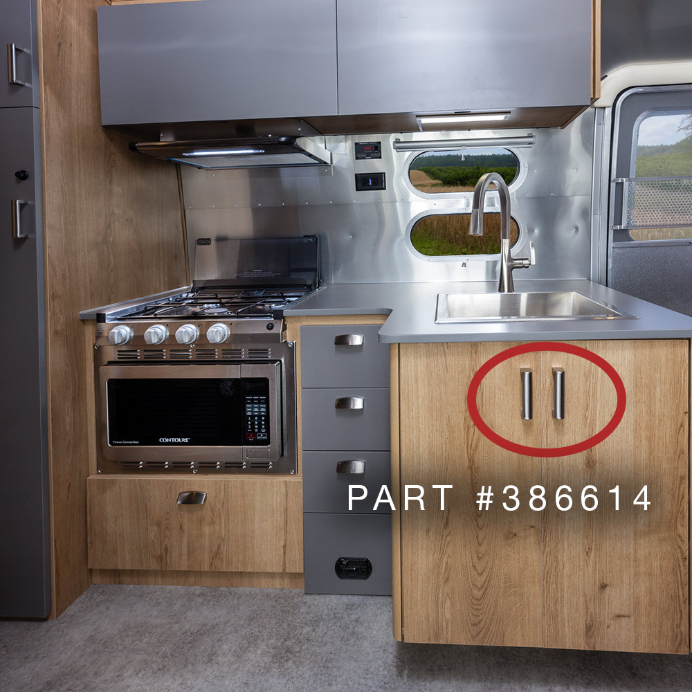 Modern RV kitchen featuring wood cabinets, a stainless stove and sink, and gray drawers. A red circle highlights a lower cabinet with two Airstream Interior Stainless Steel Handles (Part #386614).