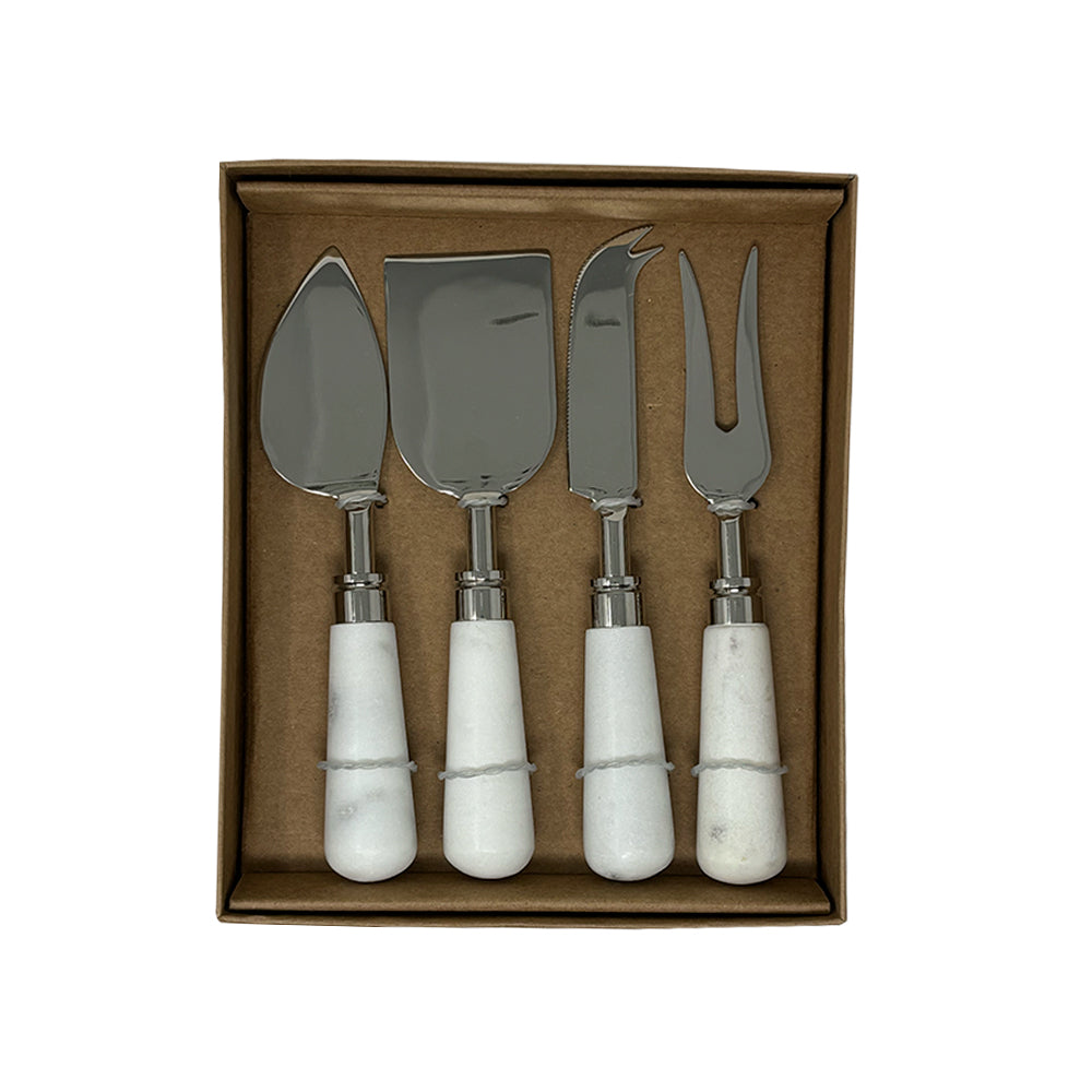 The Airstream x Pottery Barn Cheese Knife Set features four cheese knives with white handles—spreader, chisel, knife, and fork—all crafted with stainless steel blades and presented in a brown box.