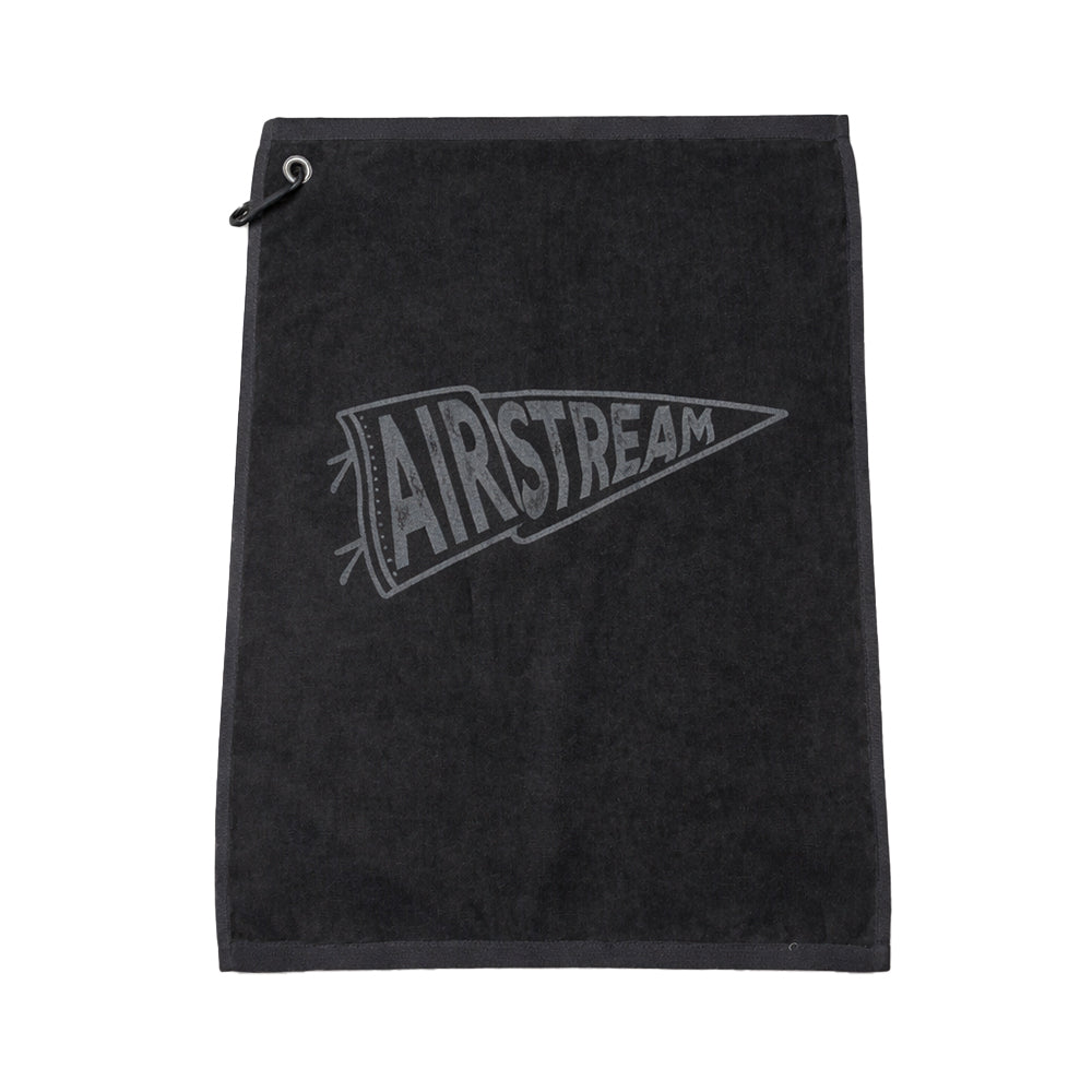 The Airstream Rally Pennant Golf Towel is a black premium golf towel featuring a convenient corner loop and the word “AIRSTREAM” printed in a stylized font inside a pennant shape—making it the perfect vintage golf accessory for any enthusiast.