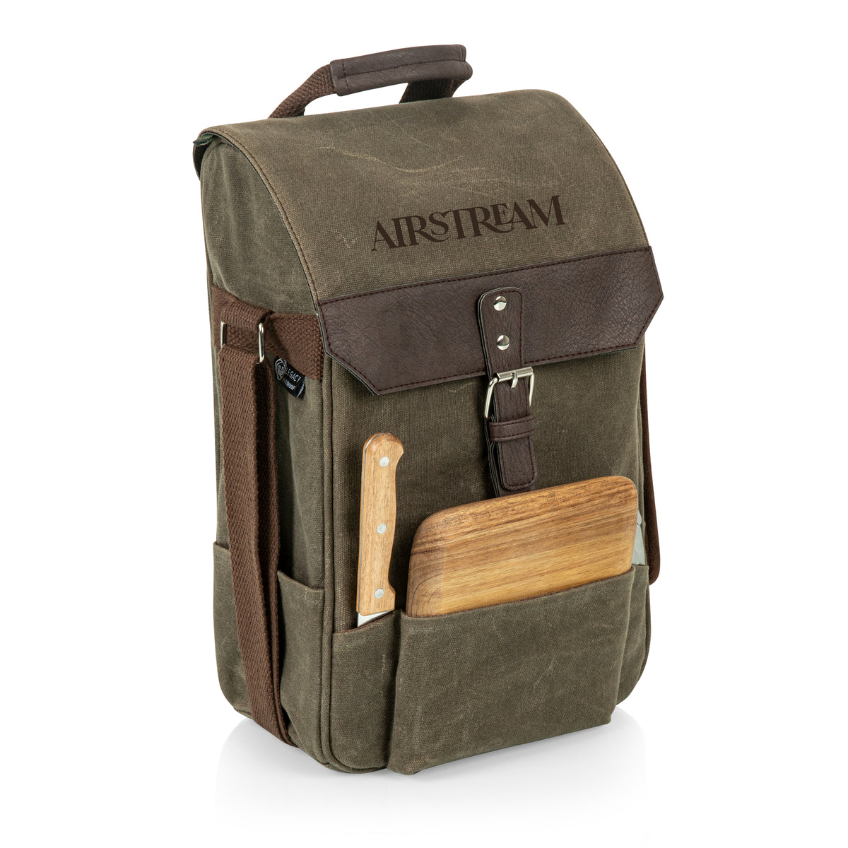 The Airstream Wine Bottle & Cheese Bag is an olive green and brown canvas backpack with “AIRSTREAM” embroidered on the flap. Designed as a stylish picnic carrier, it features a wooden cutting board and a handled cheese knife tucked into the front pocket. Side mesh pockets and a top handle are also visible.